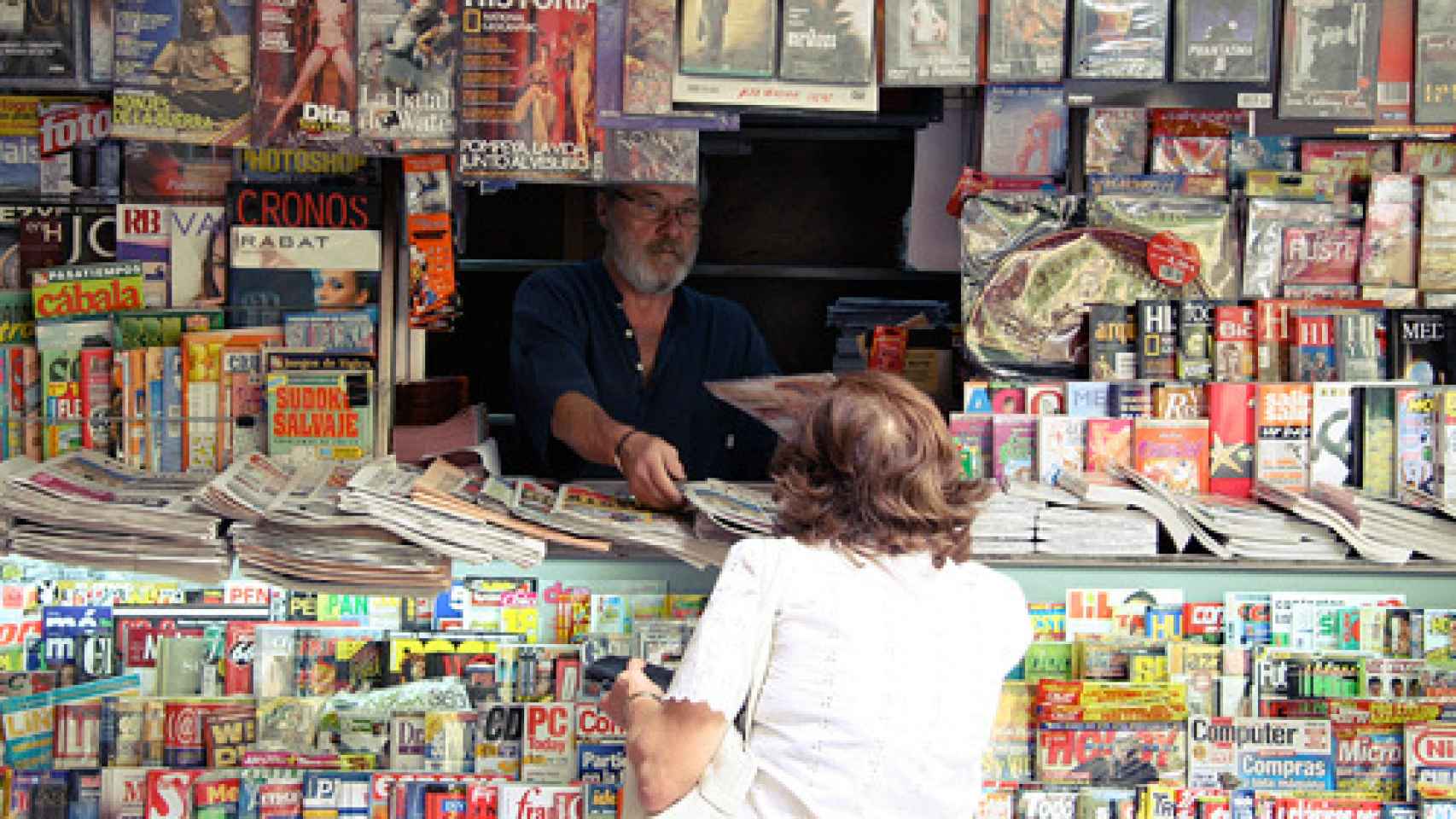 Una señora compra la prensa en un kiosko madrileño.