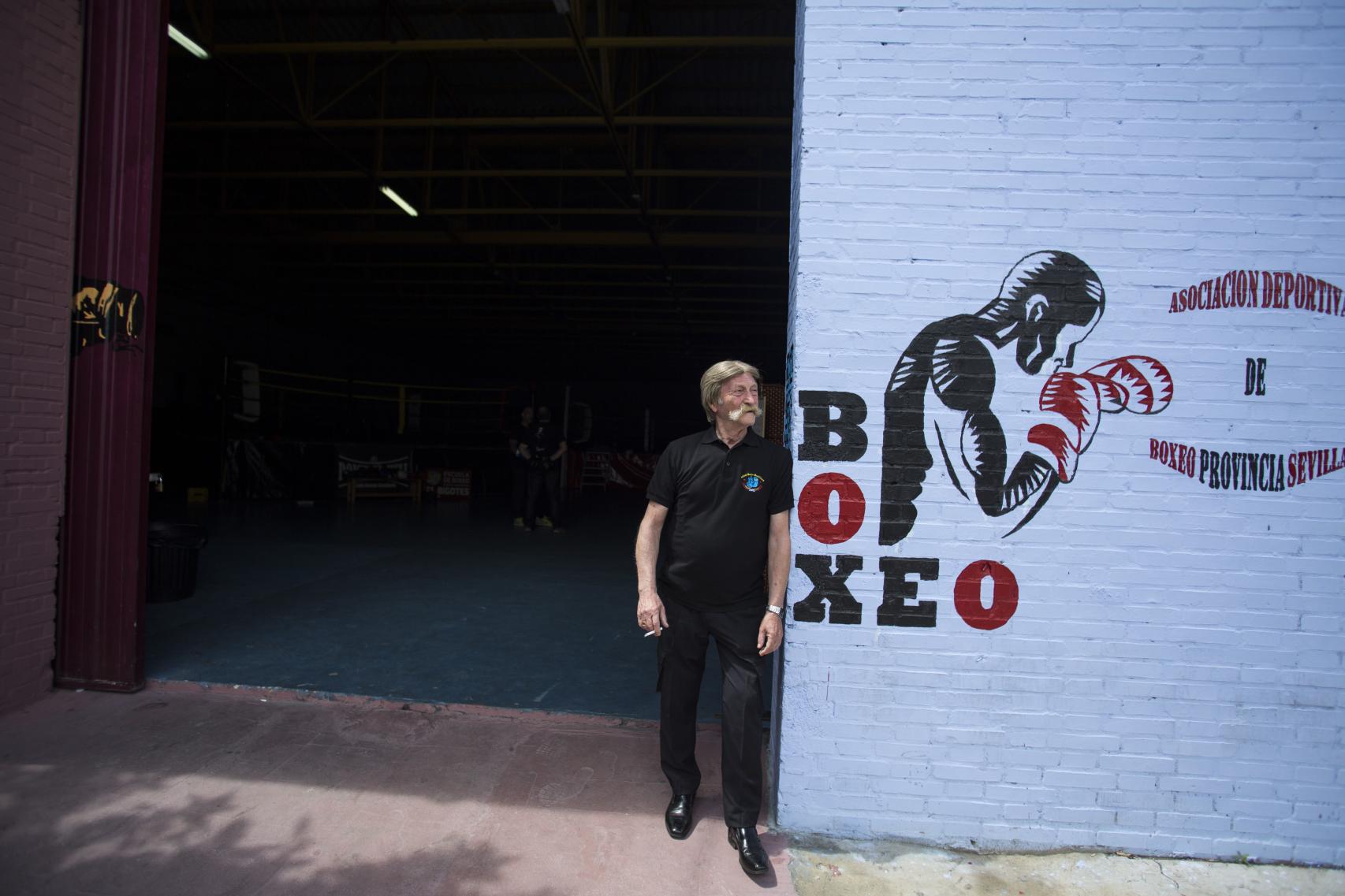 Antonio El Bigotes fumando un cigarrillo en la entrada a su centro de boxeo.