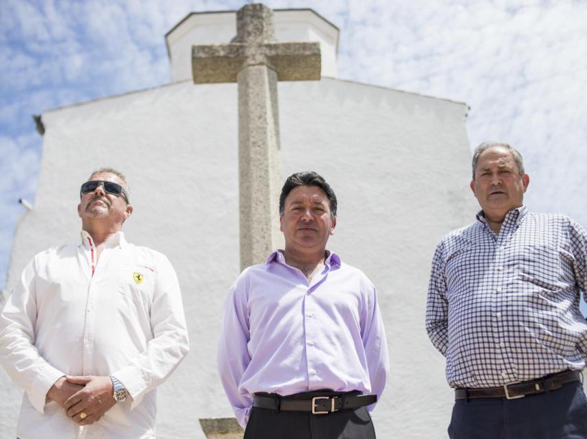 El alcalde (centro) con dos vecinos del pueblo frente a la cruz que emula a la del Valle de los Caídos y frente a la cual pretenden enterrar al dictador.
