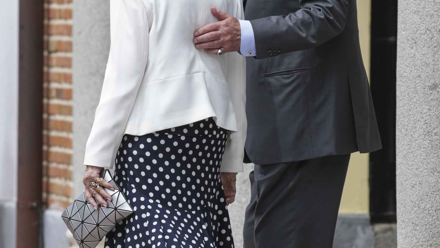 El rey Juan Carlos apoya la mano sobre la espalda de la reina Sofía.