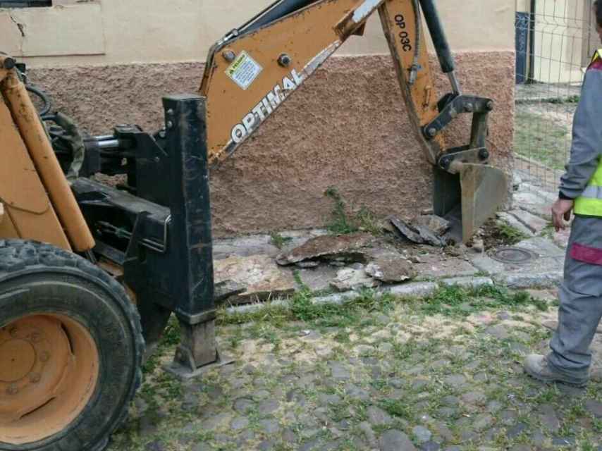 Una máquina excavadora levanta las losas originales de la acera de la plaza.