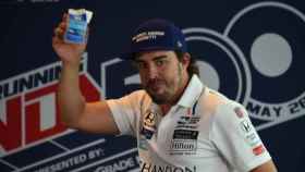 Fernando Alonso levanta la caja de leche como signo de victoria.