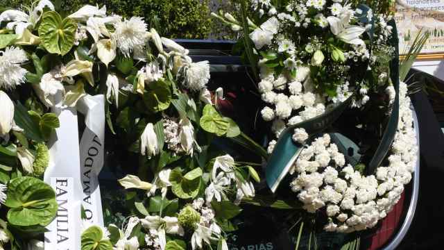 Un coche fúnebre con coronas de flores.