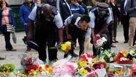 Policías británicos depositan flores en la escena del ataque terrorista.