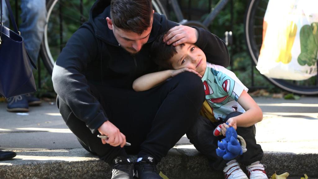 Un hombre consuela a su hijo tras ver cómo se ha incendiado la torre.