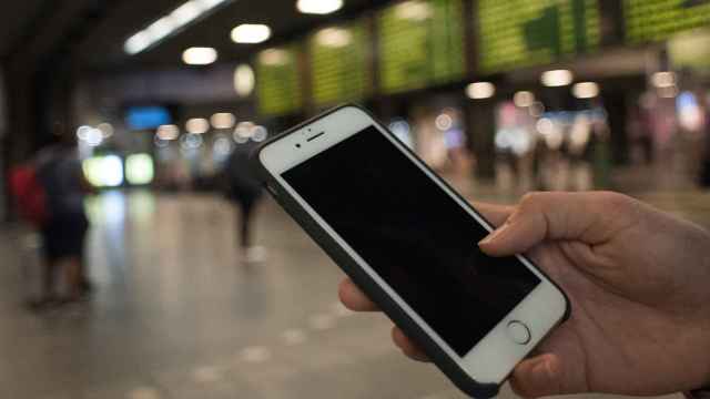 Una joven utiliza su móvil en una estación de tren