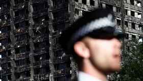 Un policía londinense frente al destruido edificio Grenfell.