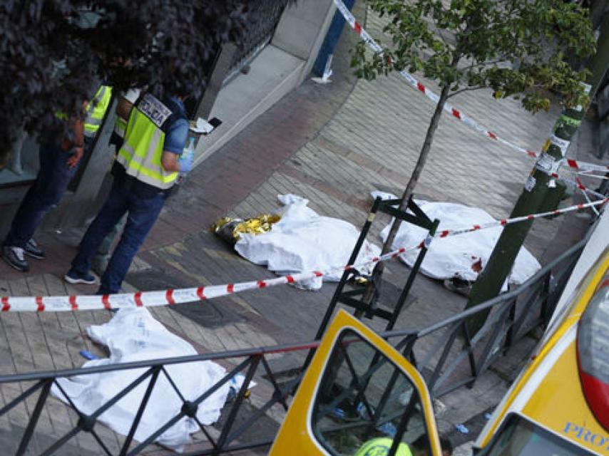 Cadáveres de los fallecidos, junto a los agentes de la Policía Científica, el día del crimen el año pasado.