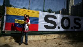 Un hombre posa con su hija y la bandera de Venezuela.