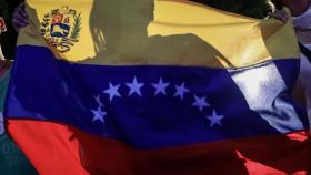 Un opositor levanta la bandera de Venezuela tras la consulta plebiscitaria.