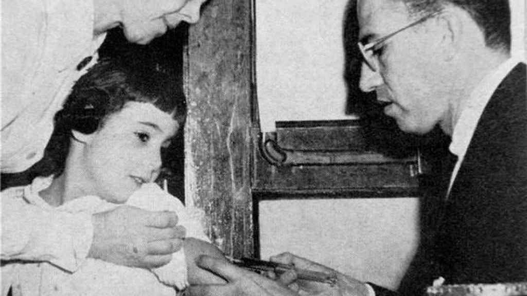 Jonas Salk vacunando a una niña.