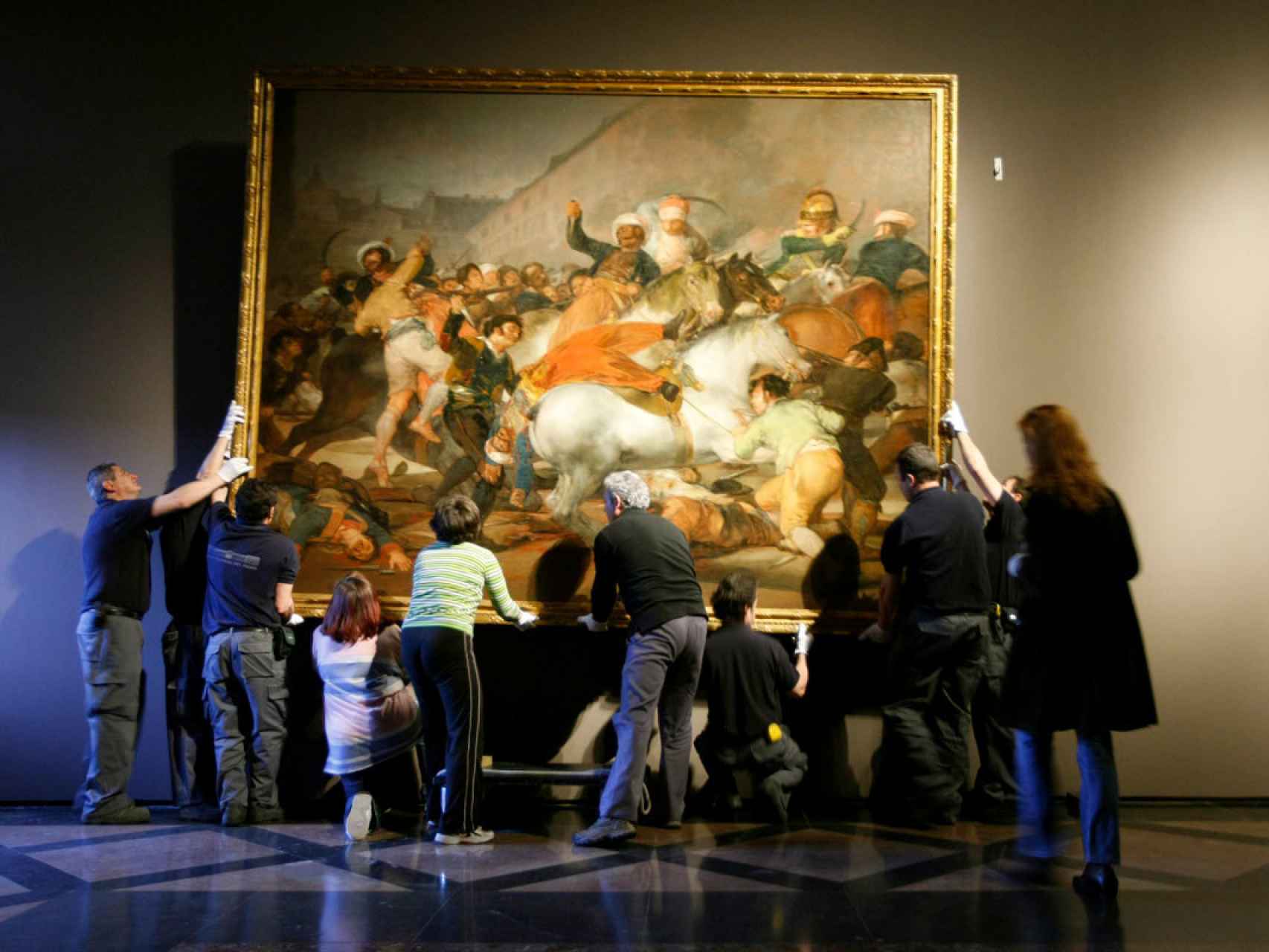 Empleados del Prado cuelgan la Carga de los mamelucos, tras ser restaurado.