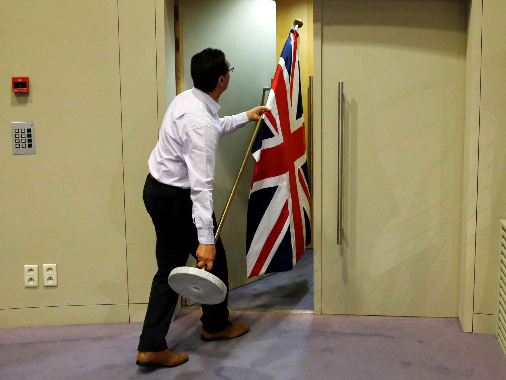 Un funcionario retira la bandera de Reino Unido en la Comisión