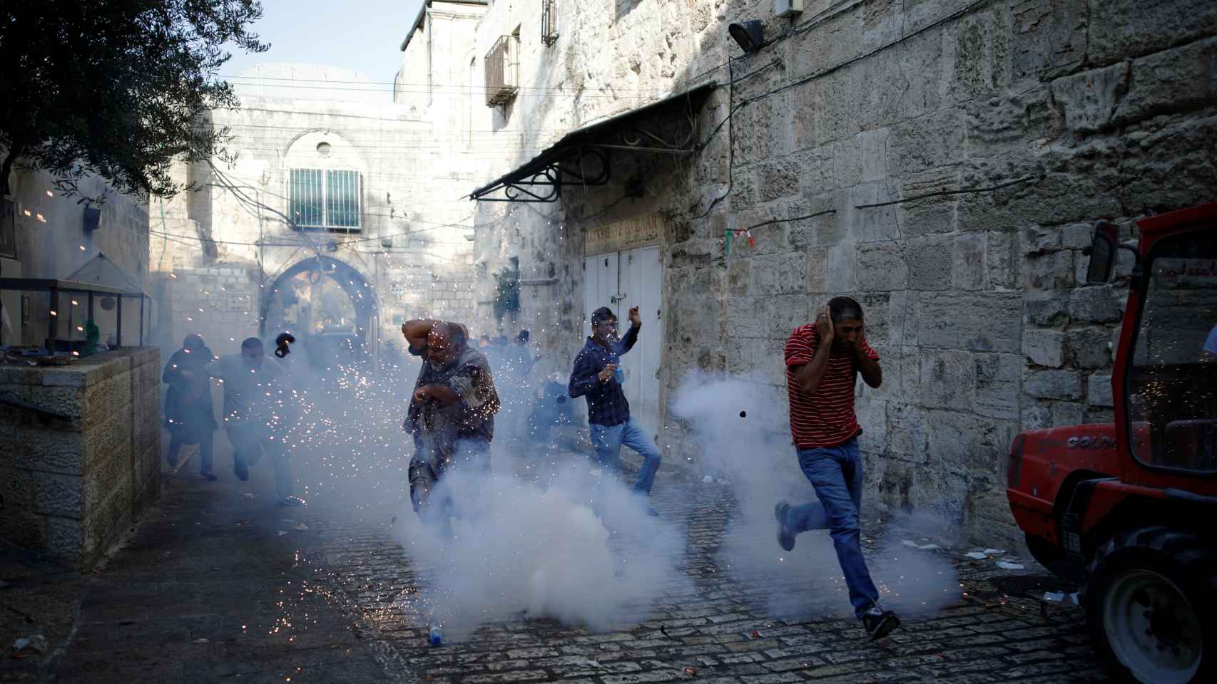Un grupo de palestinos escapa de las gases lacrimógenas de la policía israelí