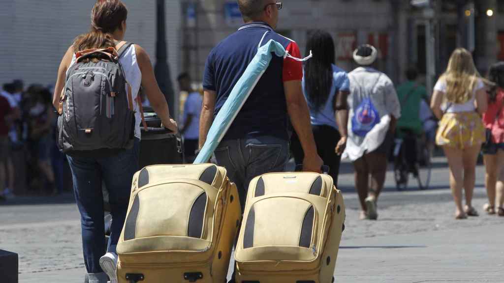 Varios turistas recorren Madrid con sus maletas.