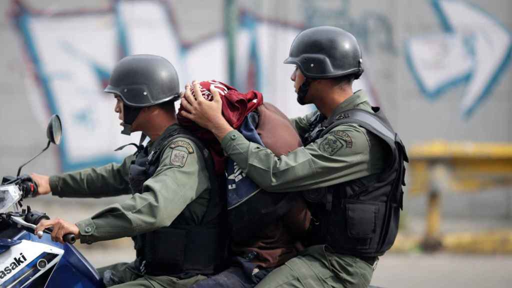 Dos policías se llevan a un manifestante de Caracas