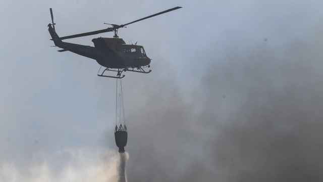 Un helicóptero descarga agua sobre un incendio forestal