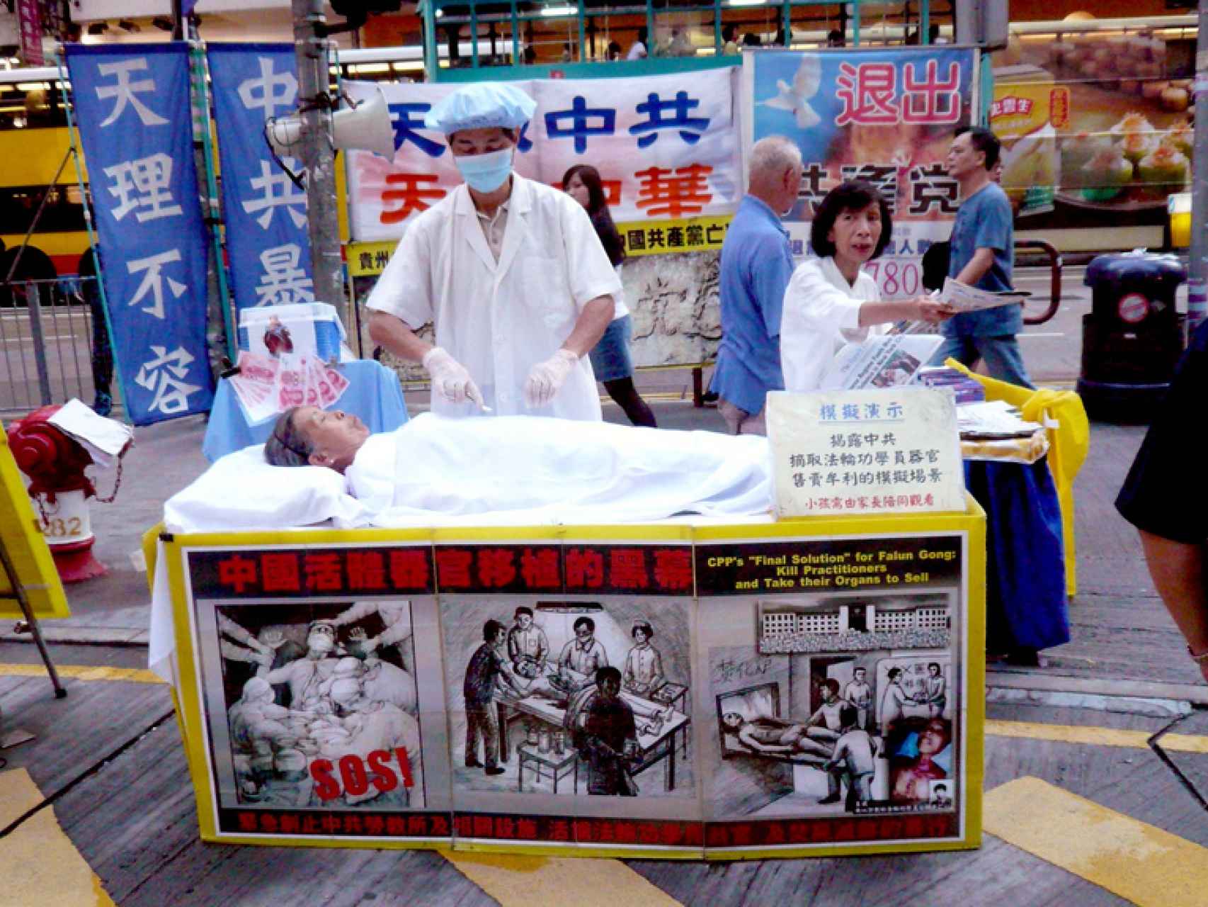 Miembros de Fulang Gong simulan una extracción de órganos como protesta.