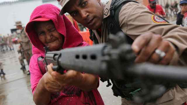 Un miembro de la milicia nacional bolivariana enseña a una mujer cómo se usa un rifle.