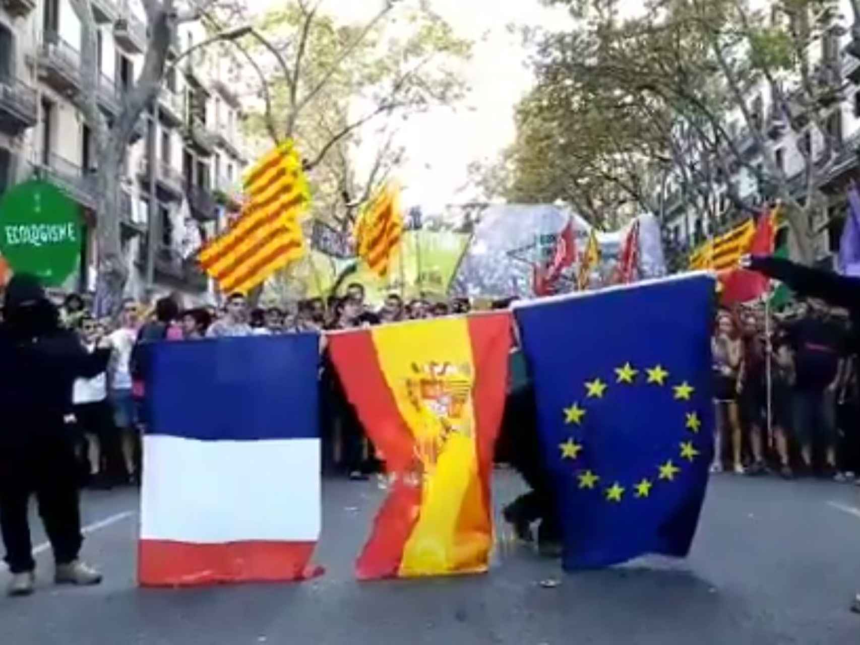 El momento en el que dos encapuchados queman la bandera de España.