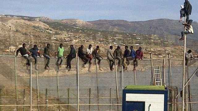 Un grupo de inmigrantes subsaharianos sobre la valla.
