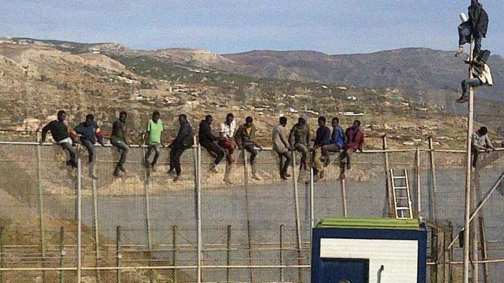 Un grupo de inmigrantes subsaharianos sobre la valla.