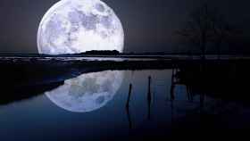 Imagen de una Luna llena reflejada en un río.
