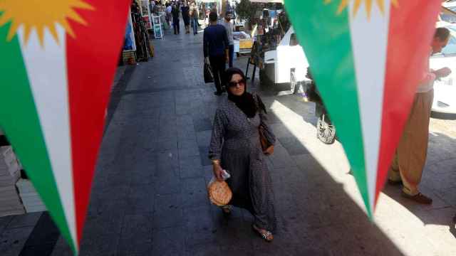 Una mujer camina en la calle, entre pancartas que apoyan el referéndum para la independencia del Kurdistán en Erbil.