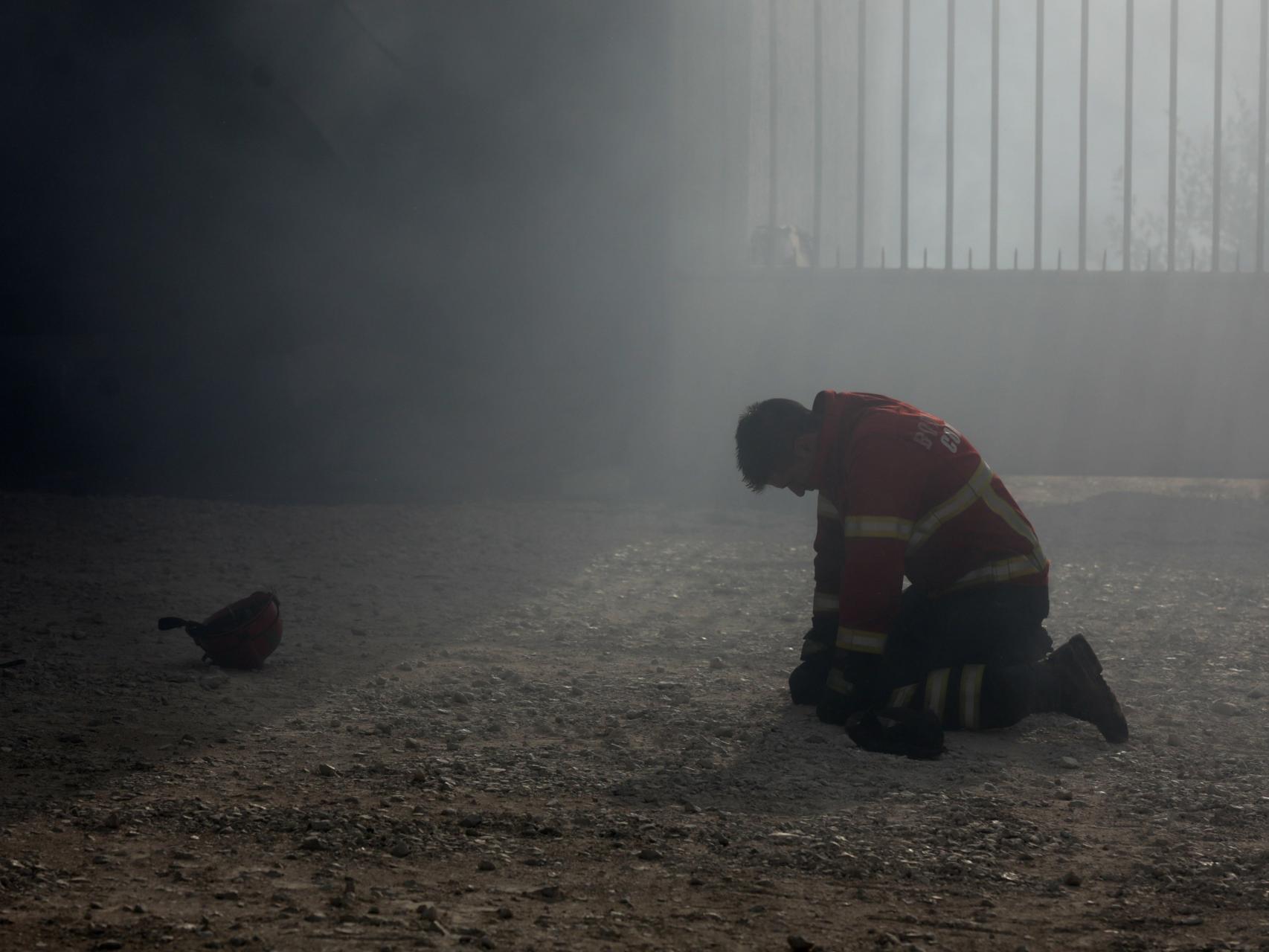 Un bombero arrodillado tras el combate al incendio en Portugal.