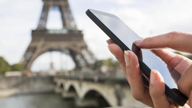 Una persona utilizando su teléfono móvil junto a la Torre Eiffel de París