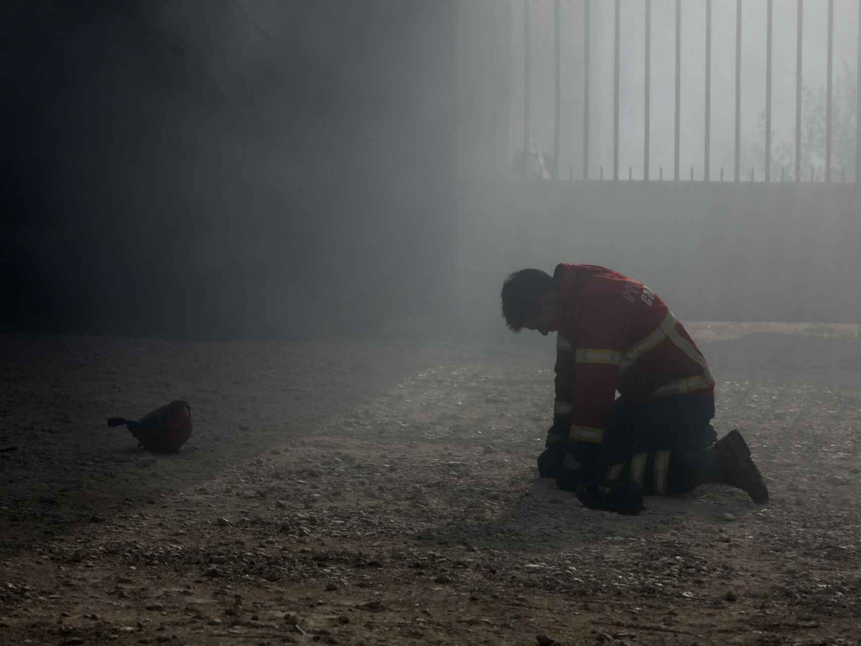 Un bombero arrodillado tras el combate al incendio en Portugal.