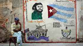 Un cubano fuma junto a una pintada con la imagen de Fidel Castro en La Habana.