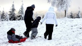 Una familia juega con un trineo en la nieve.