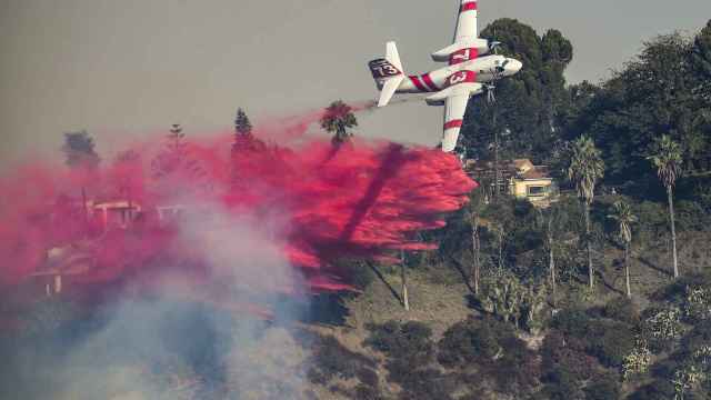 Un avión de CalFire deja caer Phos-Chek durante el incendio, en Bel Air, California.