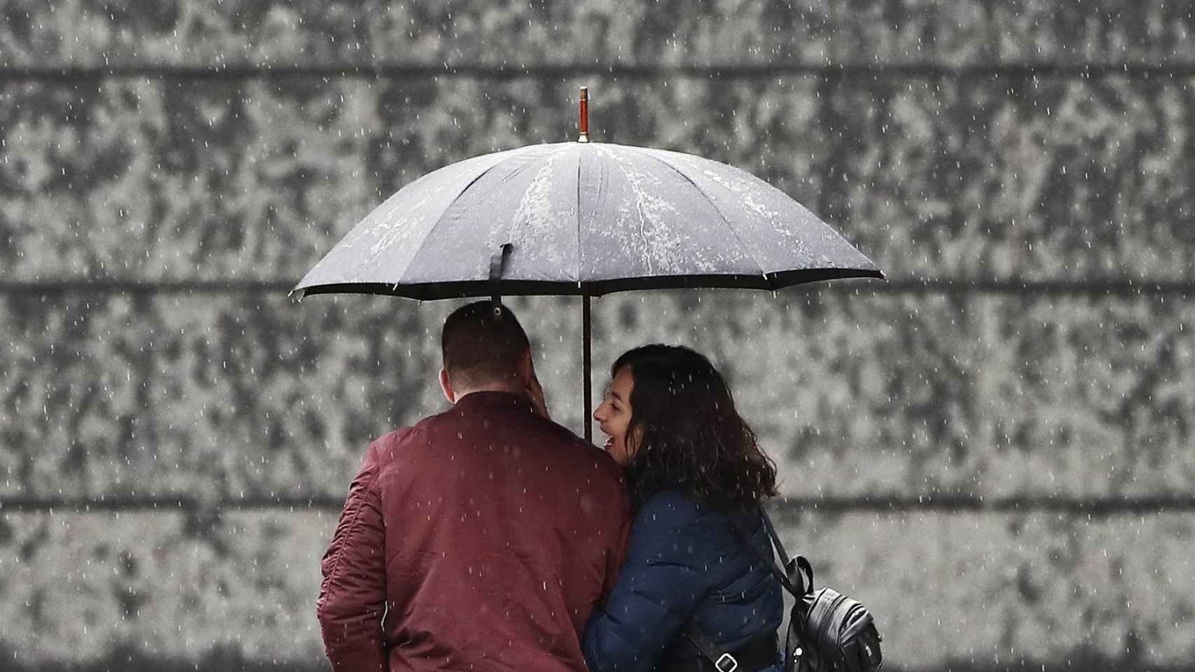 Una pareja se protege de la lluvia en Pamplona.