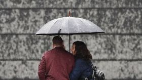 Una pareja se protege de la lluvia en Pamplona