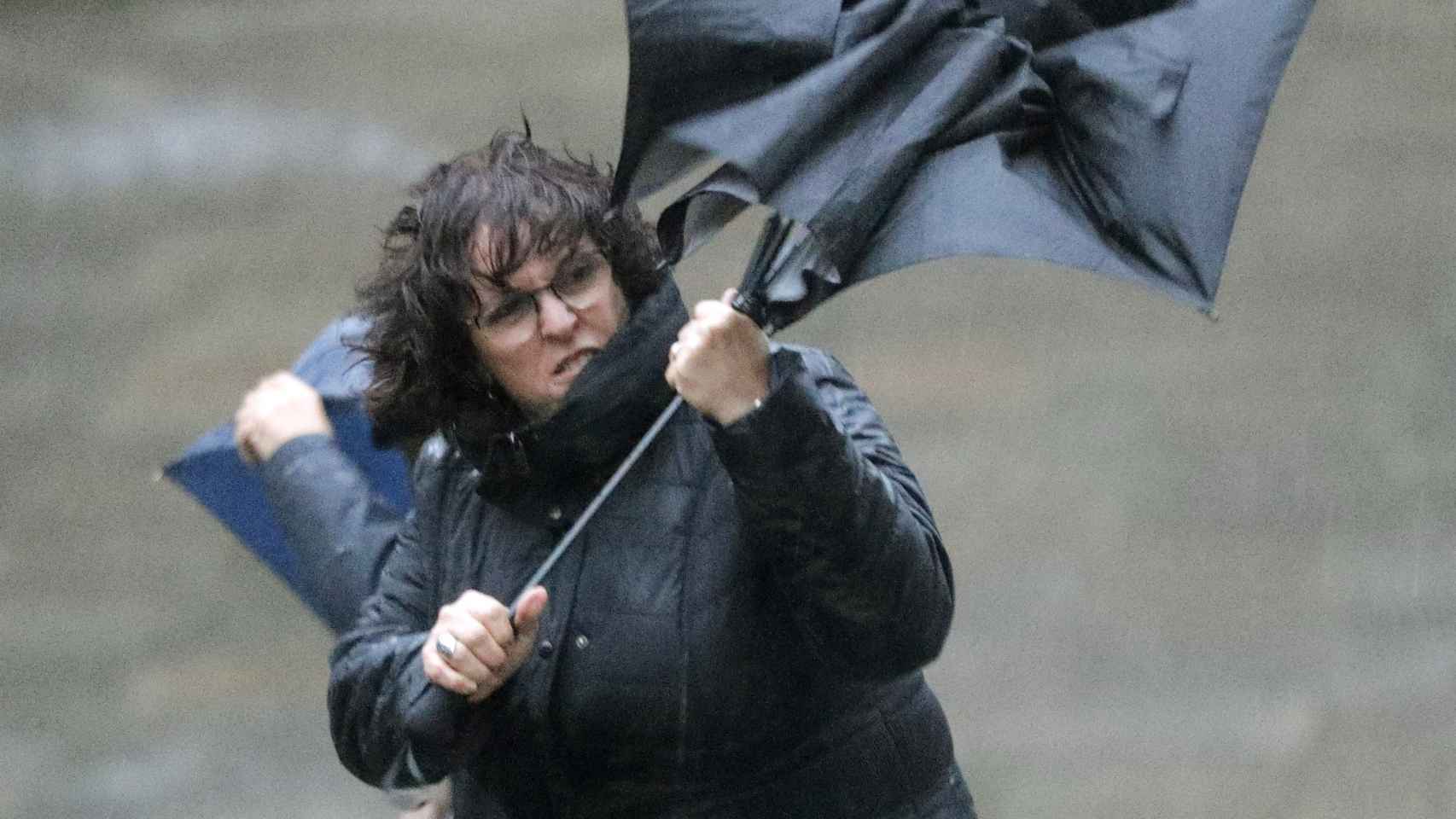 Un mujer trata de sujetar su paraguas en Santiago de Compostela