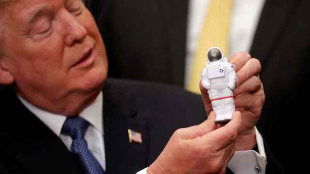 Trump sostiene un astronauta de juguete.