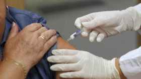 Un médico vacuna contra la gripe a una señora mayor.