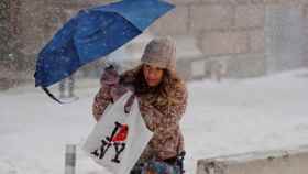 Una mujer cruza una calle de Nueva York  bajo el temporal