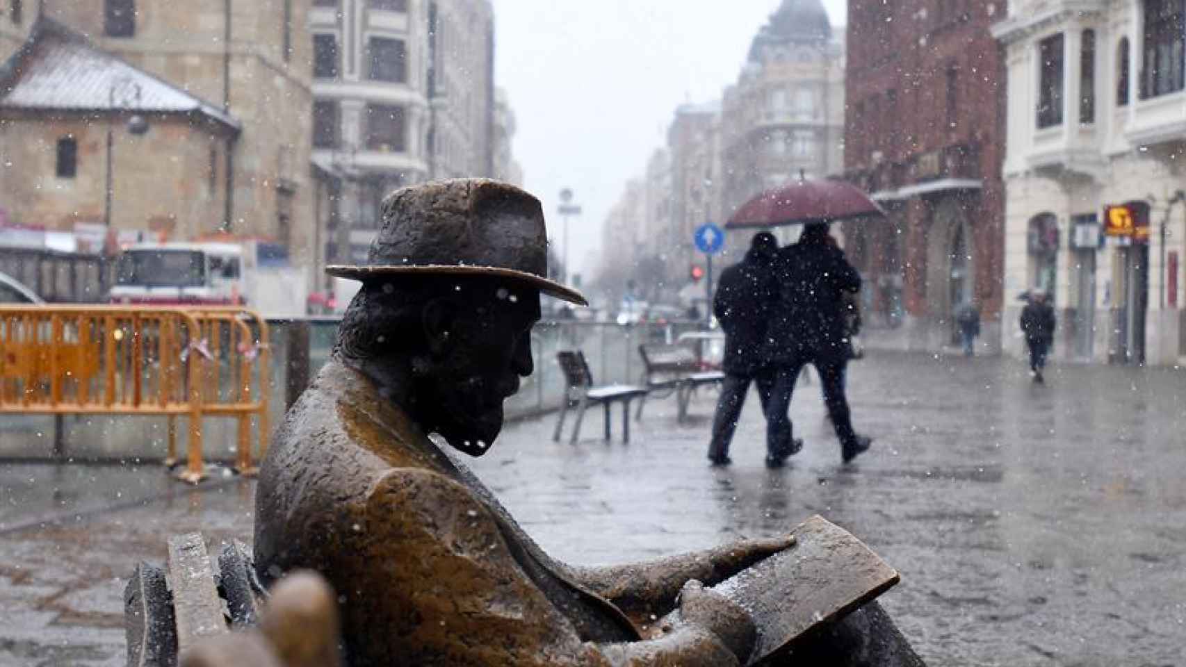 En primer plano, una escultura en León sufriendo una copiosa nevada.