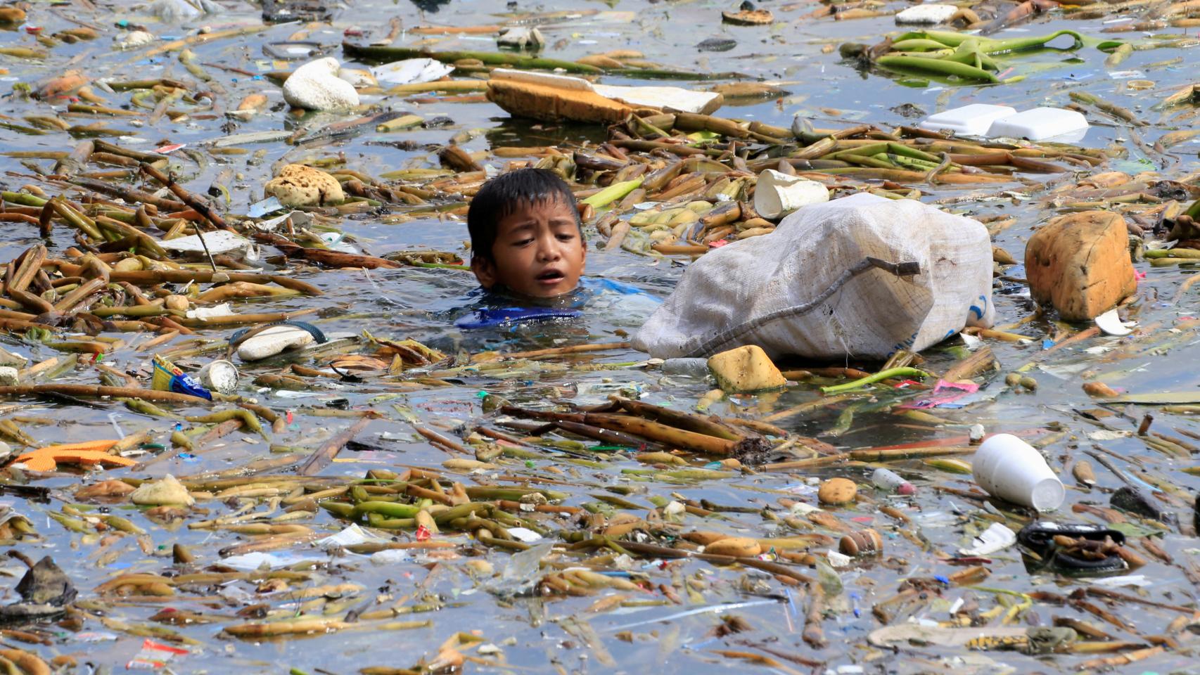 Bucear en la contaminación para ganarse la vida. Un niño filipino del poblado chabolista de Baseco nada entre los residuos de la bahía de Manila para recuperar botellas y envases de plástico que luego revenderá. REUTERS/Romeo Ranoco
