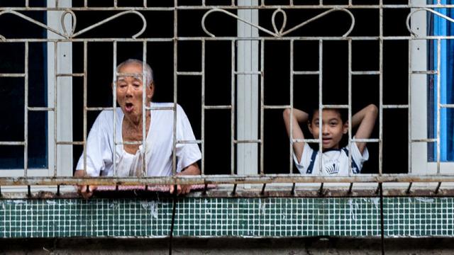 Un anciano observa la calle junto a su nieto en una ciudad china.