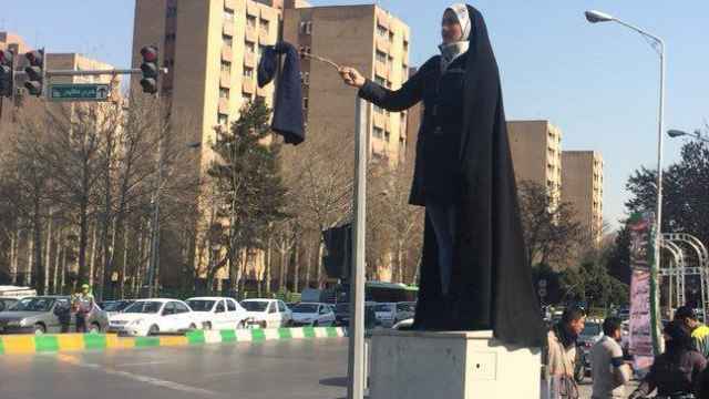 Una de las mujeres que ha protestado subida a una caja de la luz contra el chador.