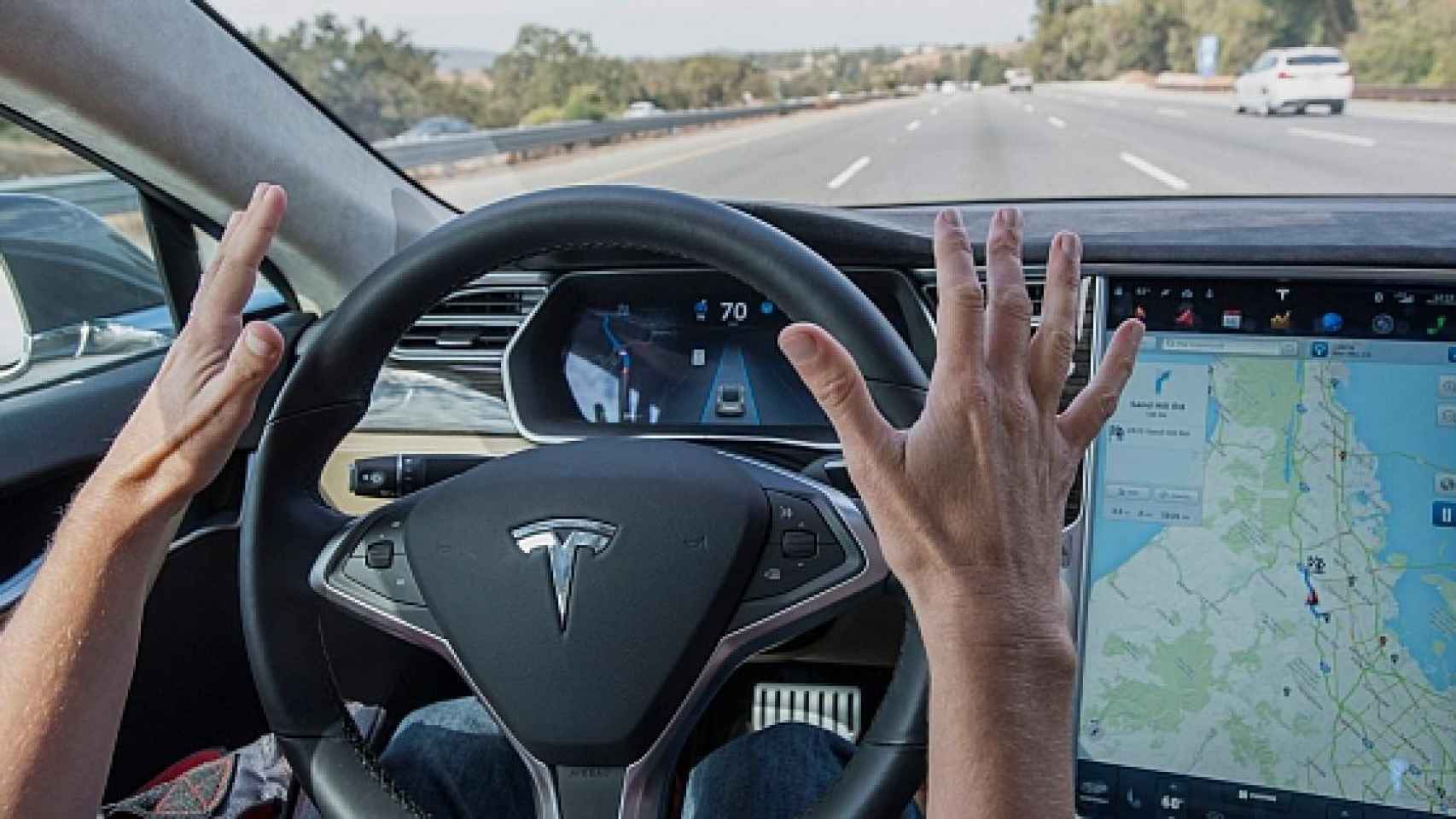 Persona sacando las manos de un volante Tesla.