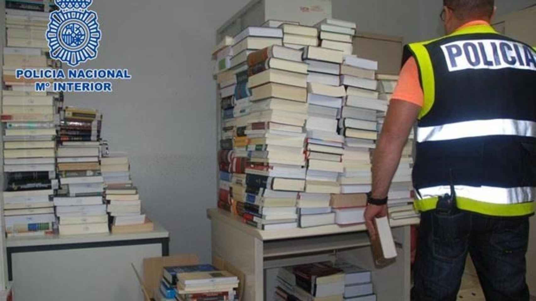Un agente, con los más de 700 libros de texto recuperados después de que fueran robados de un colegio.