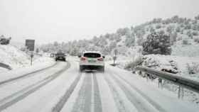 Distintos vehículos circulan por una carretera cubierta de nieve.