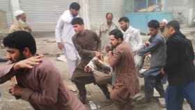 Varias personas evacúan a un herido en un atentado en Kabul.