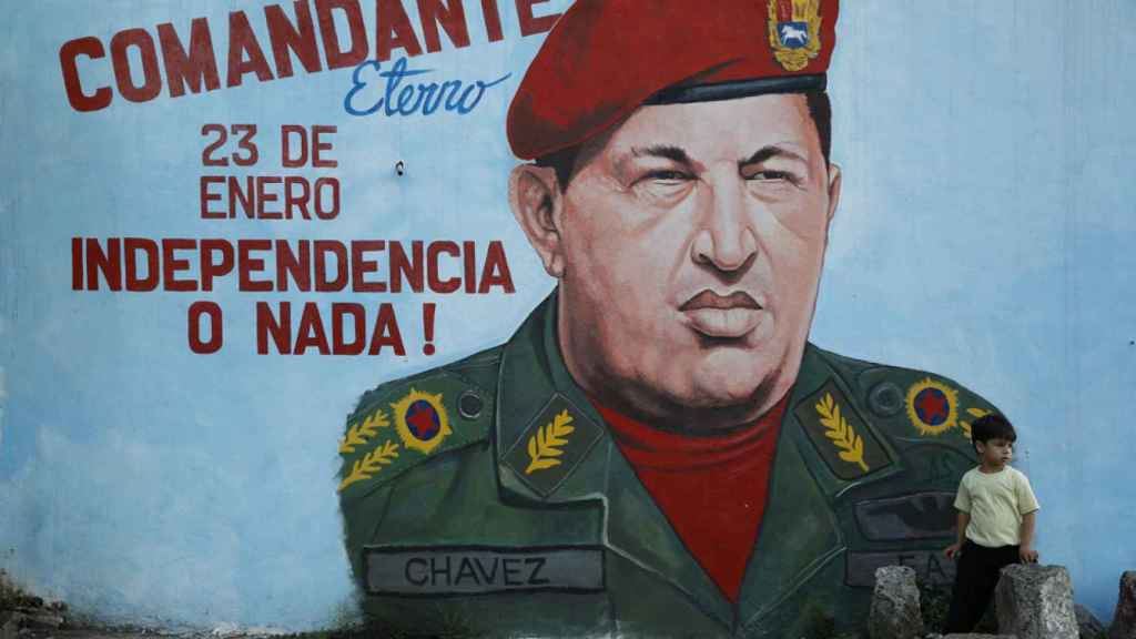 Un niño delante de una pintada de Hugo Chávez en Caracas.