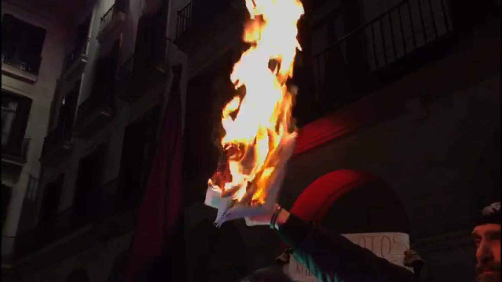 Un policía sostiene una foto ardiendo del SUP en una manifestación de Jusapol